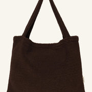A dark brown fleece shoulder bag with a soft, textured sherpa-like finish and a single integrated shoulder strap, shown against a plain white background.