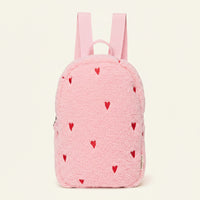 A pink fleece backpack with small red heart patterns, featuring dual shoulder straps and a top carry handle, shown against a plain white background.